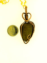 Load image into Gallery viewer, Copper Den Stone Jewelry's #200 Dendritic Dolomite with chain features a teardrop-shaped pendant wrapped in oxidized copper wire, which elegantly forms a heart shape at the top to highlight its natural beauty. The dark stone pendant lies next to a 10-cent Canadian coin for size comparison.