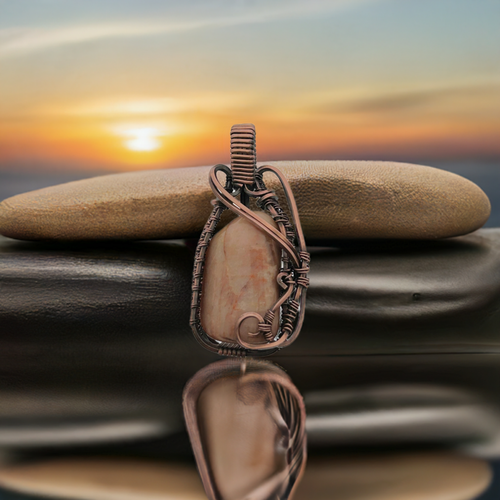 An Orthoclase Sunstone pendant wrapped in oxidized copper wire.